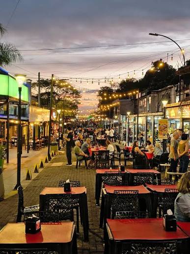Rua com mesas ao ar livre e luzes acesas ao entardecer na Argentina